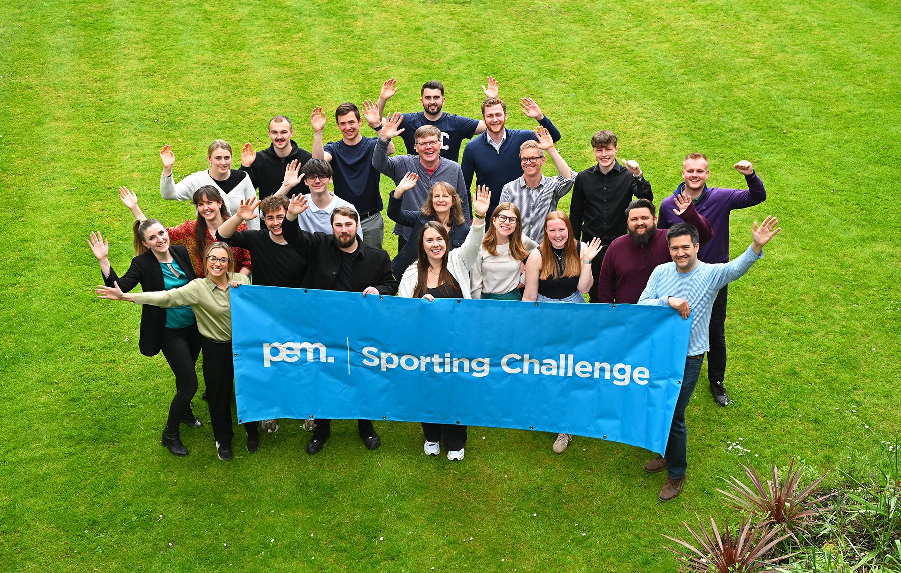 PEM employees stand behind blue banner that reads "PEM Sporting Challenge"