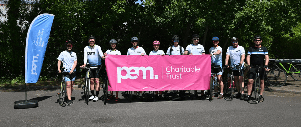 group of cyclists behind banner reading PEM charitable trust