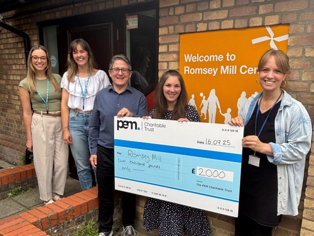 5 people standing in front of a sign reading Romsey Mill, holding a large cheque for £2000